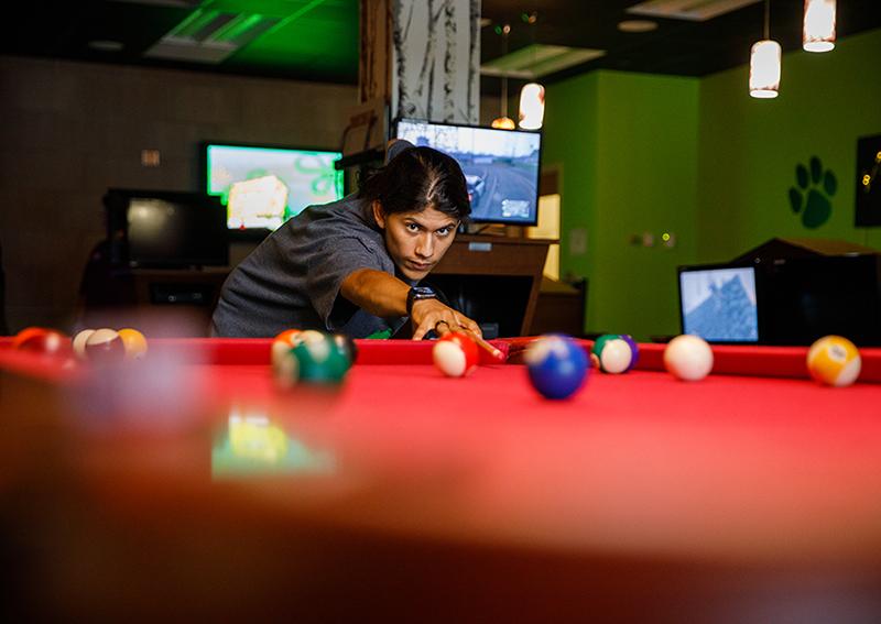 student playing billiards in game room